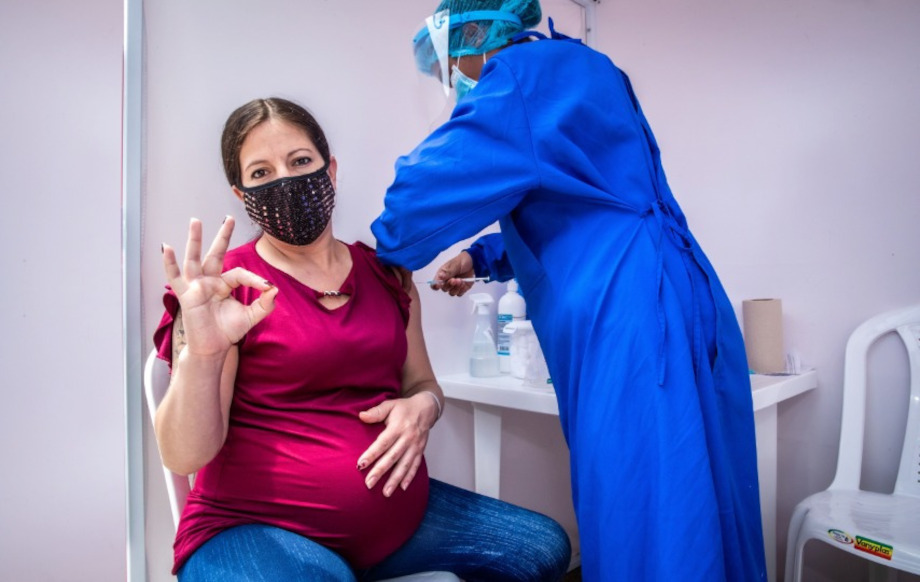 Enfermera vacunando a una mujer en estado de embarazo