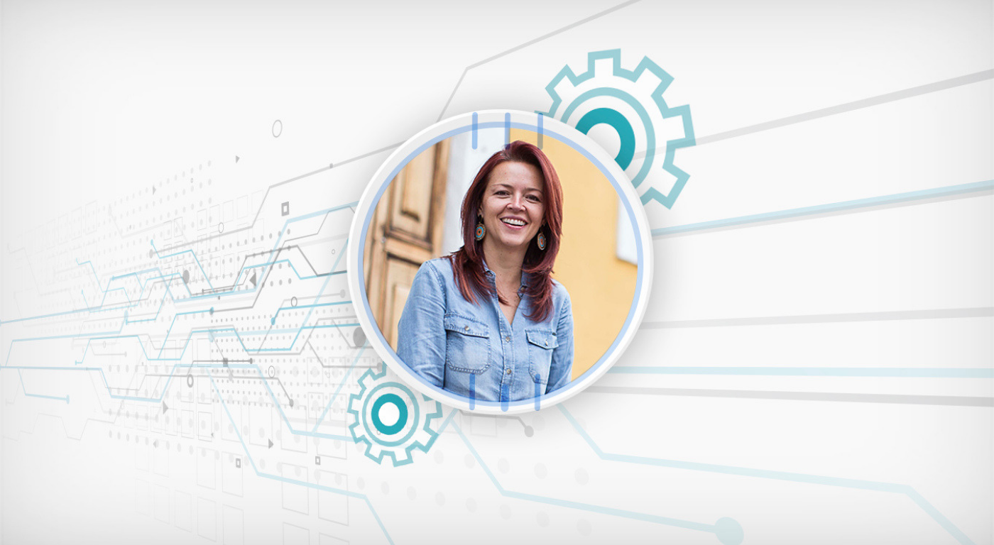 Retrato de mujer blanca, pelirroja, posa sonriente frente a la cámara.