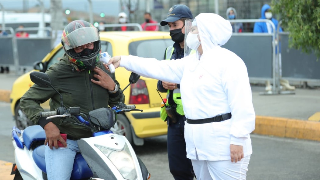 Funcionaria tomando la temperatura de un motociclista en la vía.