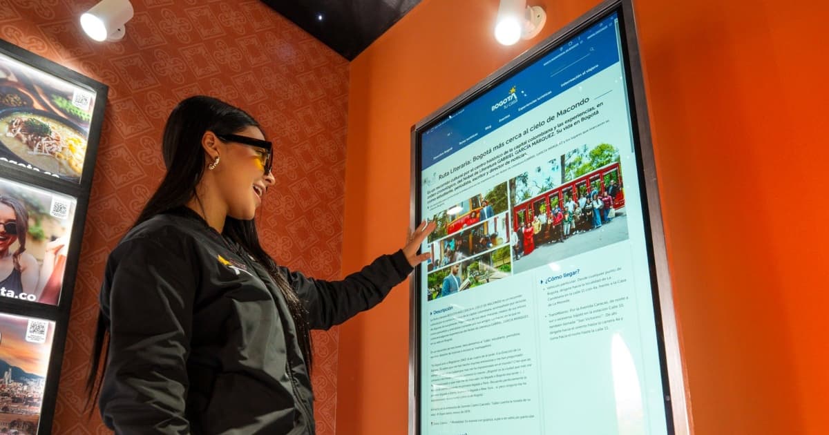Una mujer accediendo a unas pantalla táctil con información de turismo de Bogotá.