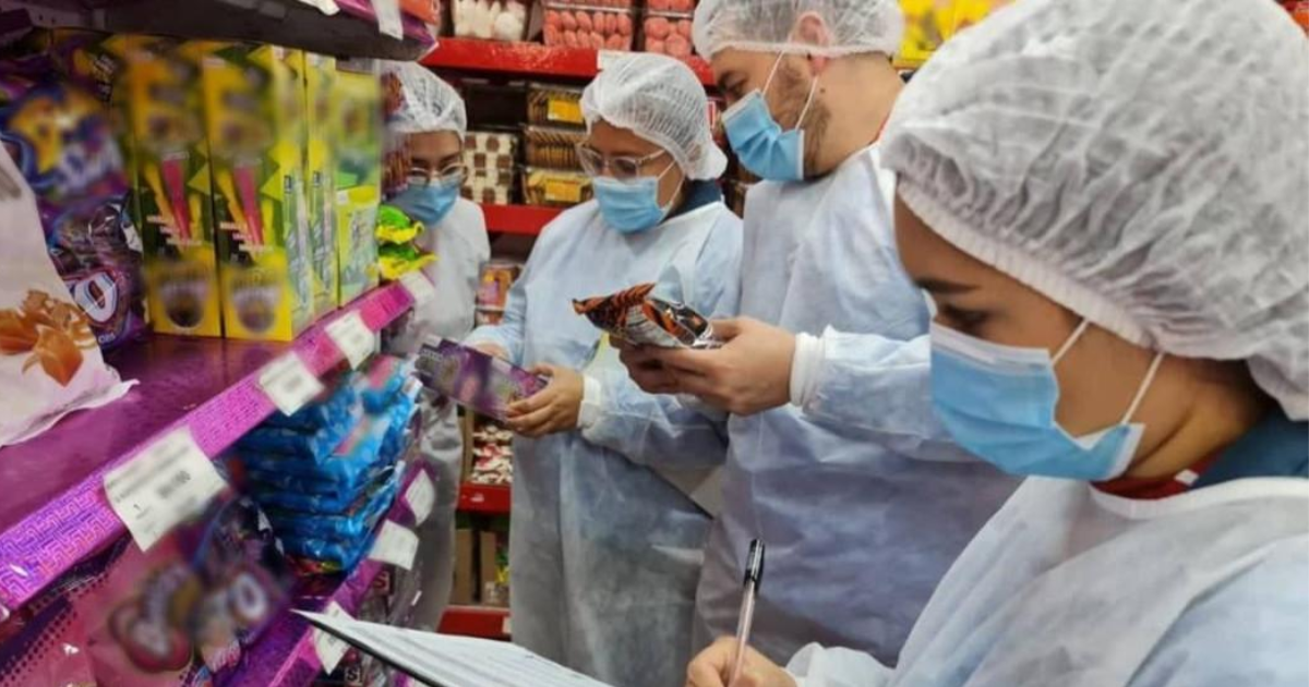 Foto de funcionarios de salud inspeccionan productos en un establecimiento para verificar su calidad y garantizar la seguridad alimentaria durante Halloween.