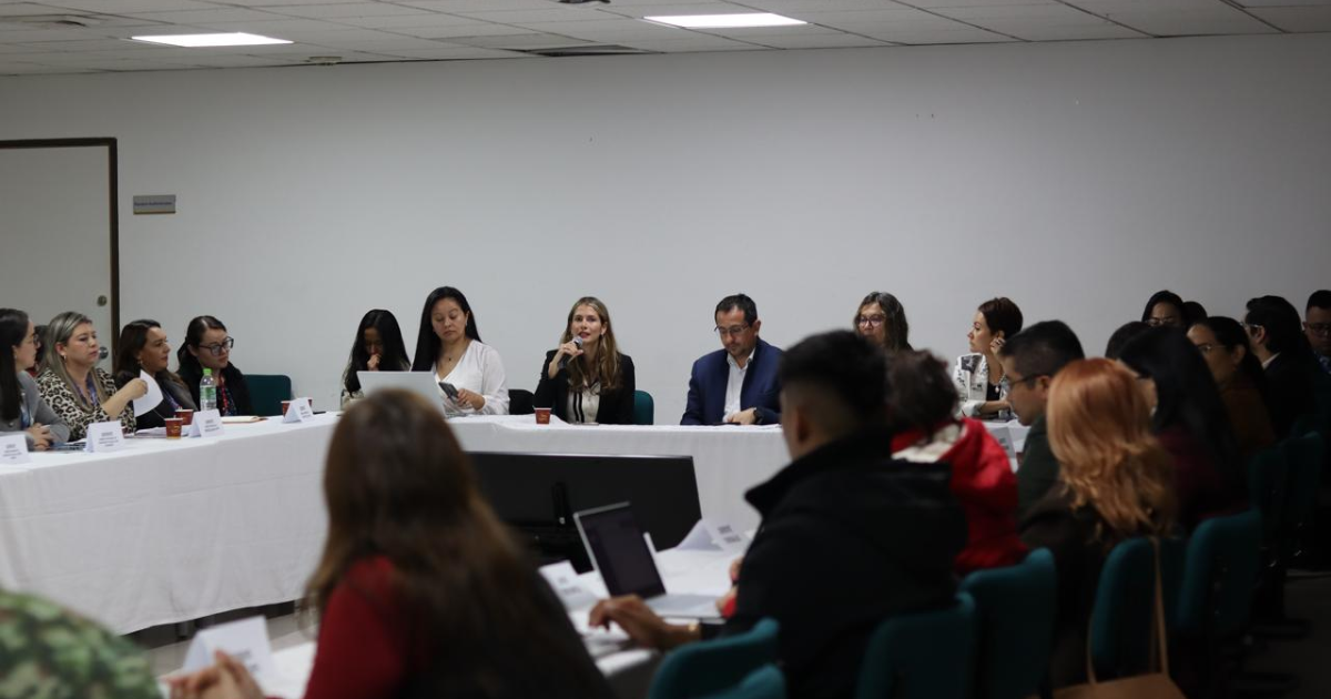 Foto de una mujer hablando en un auditorio sobre la vacunación en Bogotá