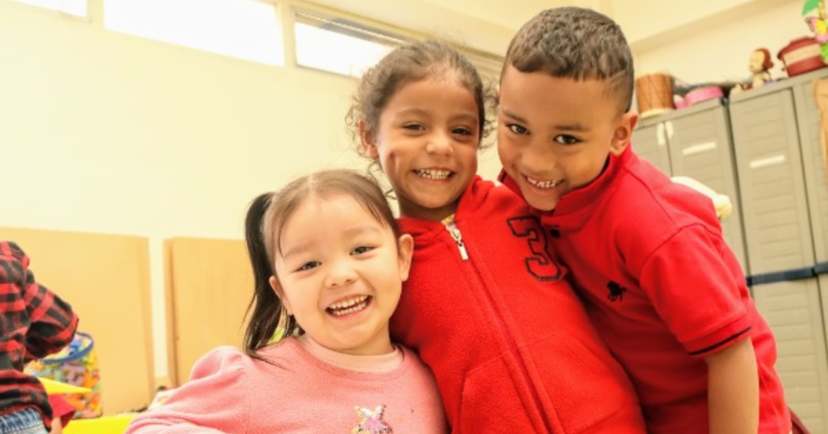 Imagen de dos niñas y un niño sonriendo 