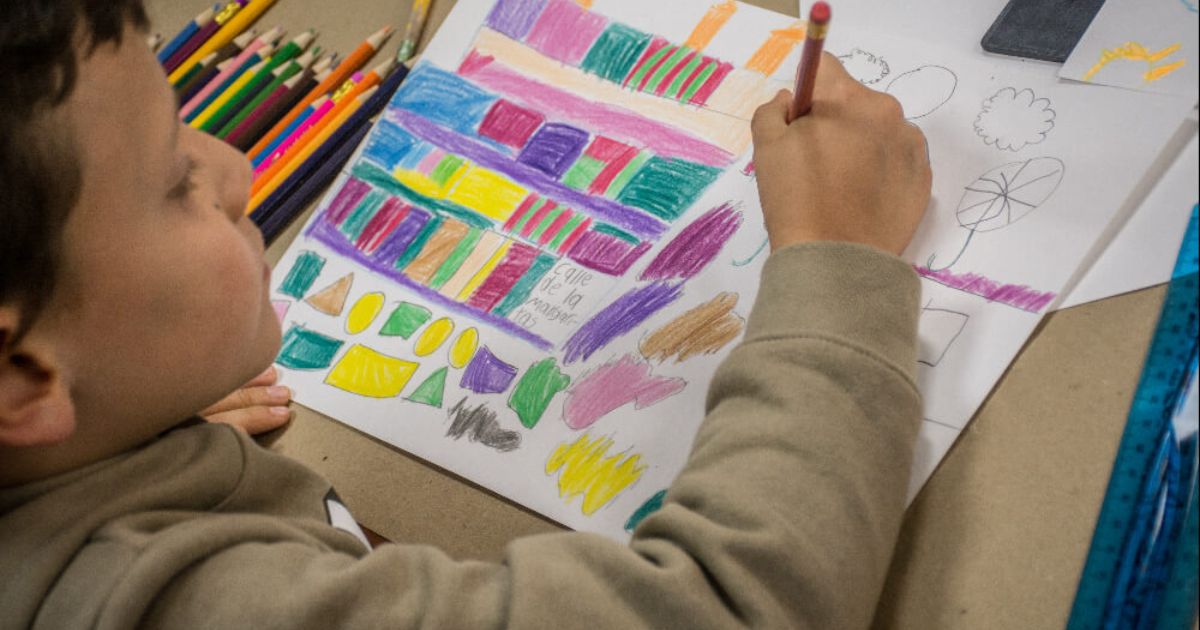 Imagen de niño dibujando sobre una hoja