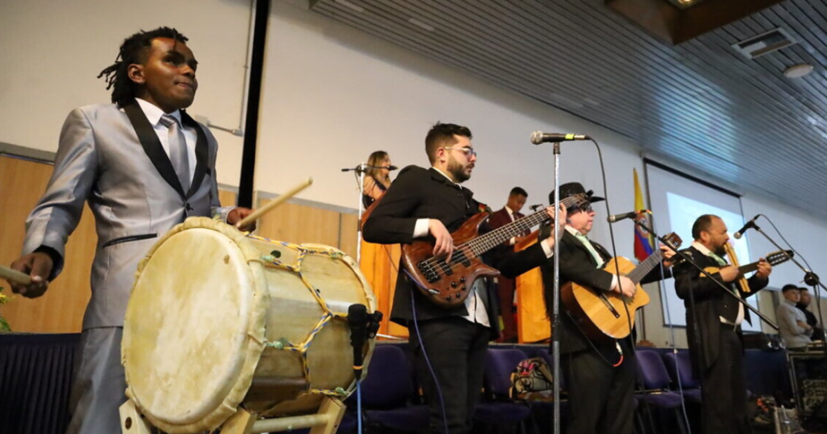 Imagen de una orquesta de personas con discapacidad tocando en tarima.
