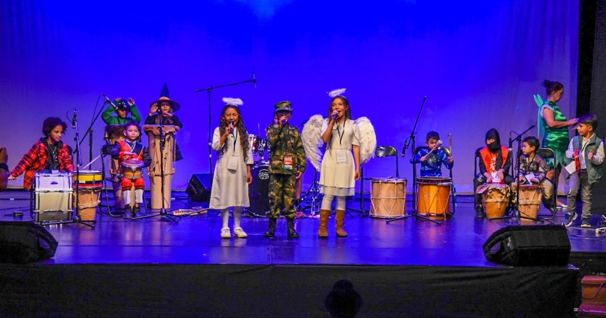 Imagen de niños y niñas cantando disfrazados en una tarima