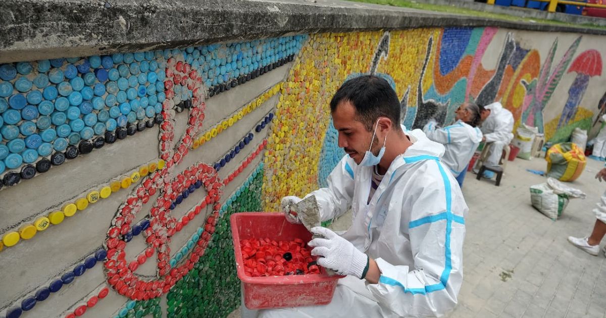 Imagen de ciudadanos en proceso de superación de vida en calle en la elaboración del mural de la estación Bicentenario de TransMilenio. 