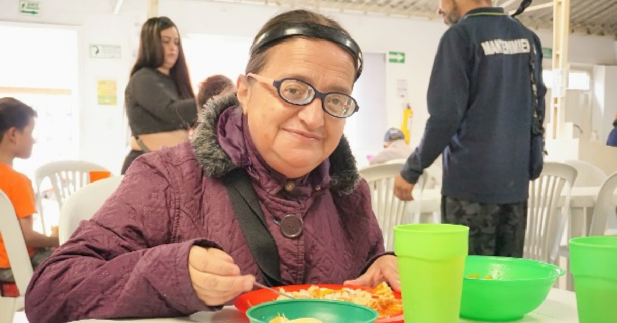 Imagen de una mujer sonriendo mientras consume un alimento.