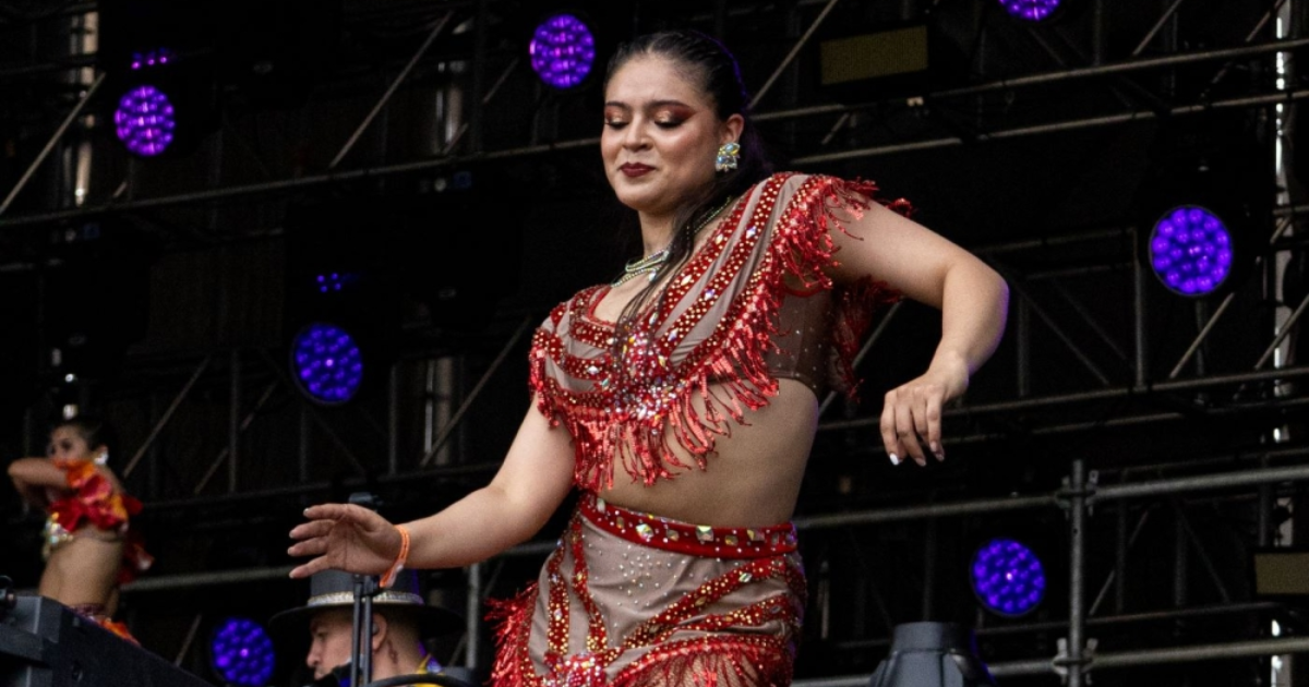 Imagen de mujer en esenario bailando salsa con la ropa caracteristica de estos bailarines