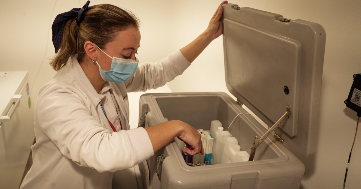 Foto que muestra una enfermera revisando un recipiente con vacunas 