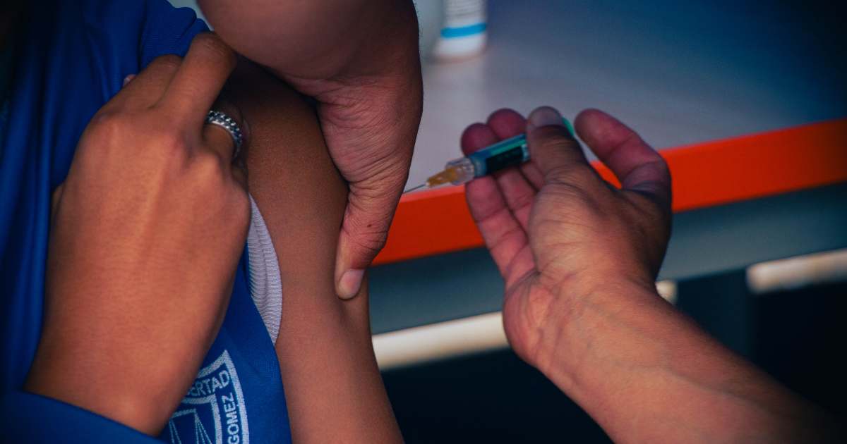 Foto que muestra una persona que le están colocando una vacuna en su brazo
