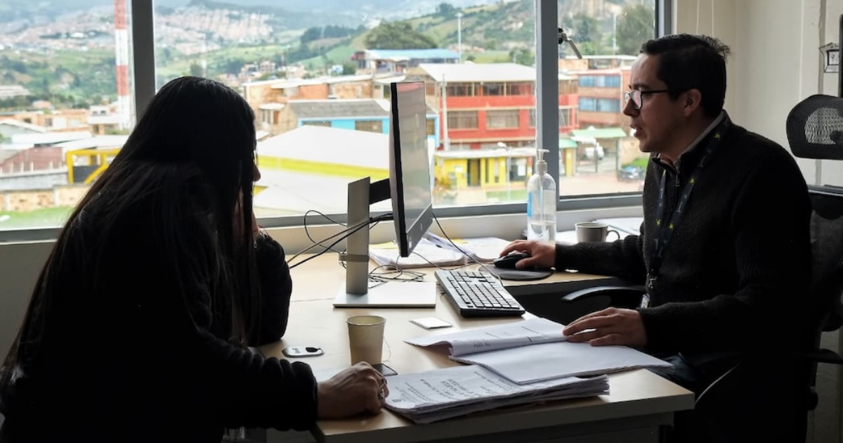 Imagen de dos personas en una oficina en medio de un computador