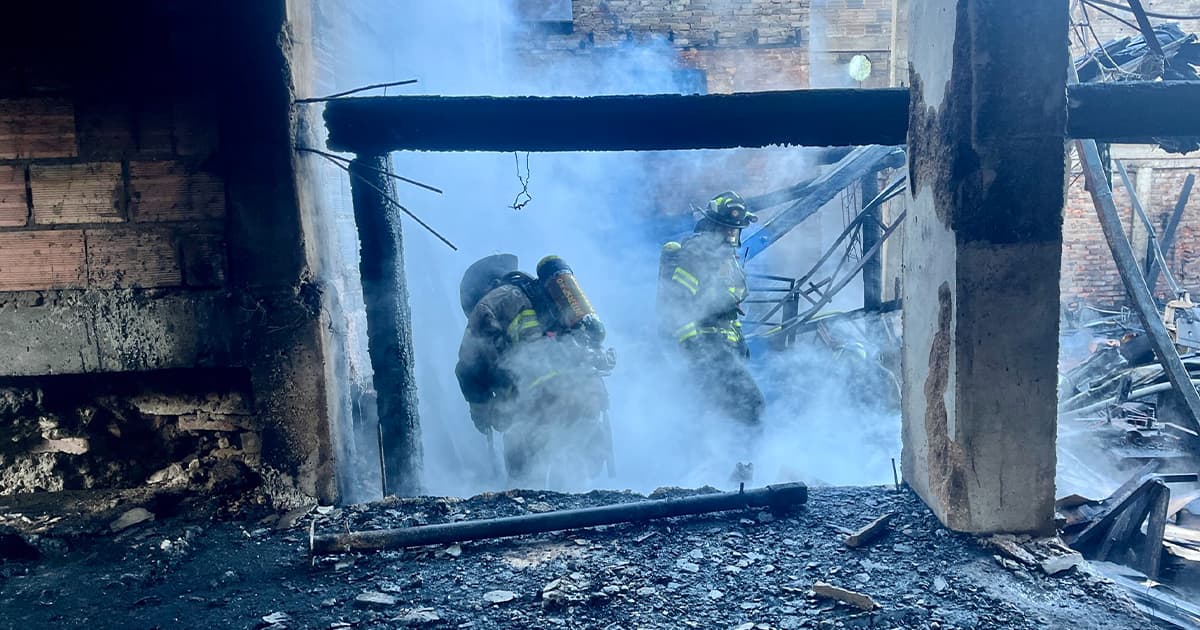 En la foto dos bomberos apagando un incendio en Las Cruces