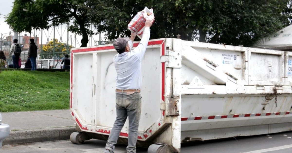 Foto que muestra una persona dejando una bolsa en un ecopunto