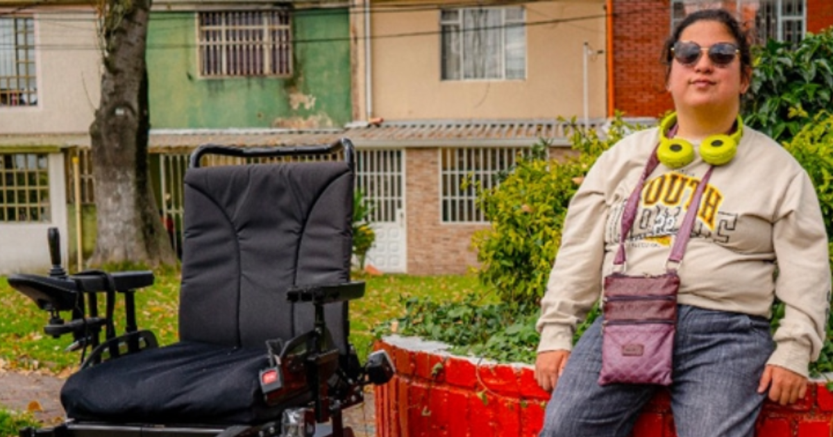 Imagen de una mujer en condición de discapacidad junto a una silla de ruedas