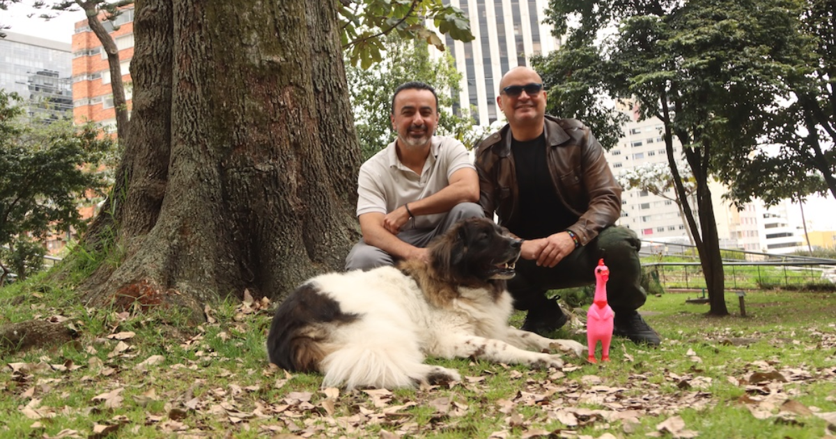 Imagen de dos personas junto a un perro de compañía