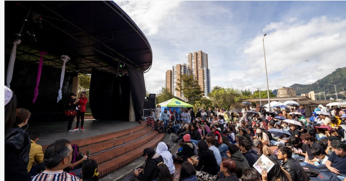 Imagen de un escenario donde abajo hay muchas personas disfrutando de un evento.