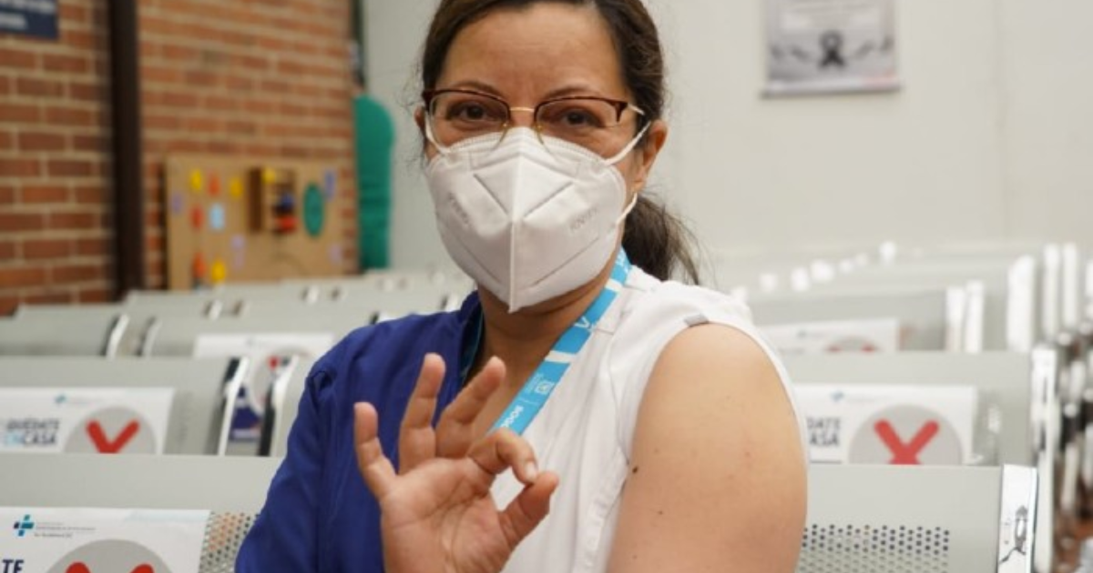 Imagan de mujer que ha sido vacunada indicando con su mano su aprobación.