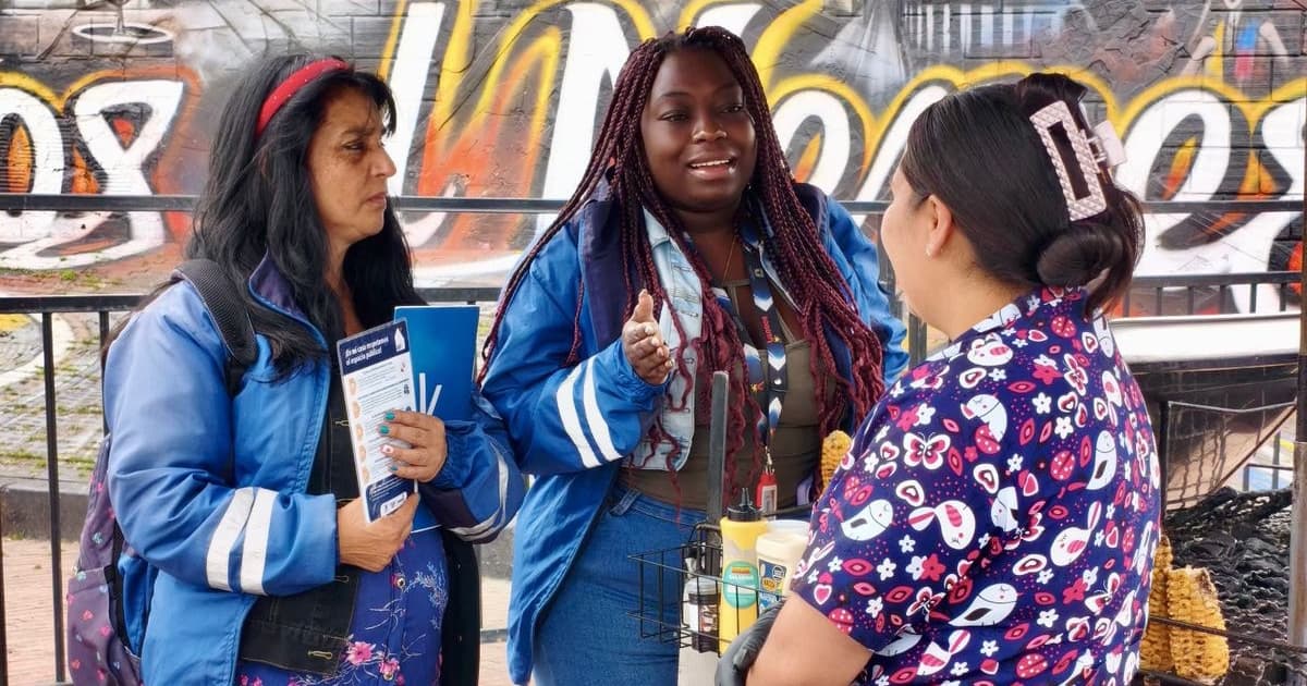 Foto de funcionarias del IPES con una vendedora informal socializando la guía para el uso responsable del espacio público en Bogotá.