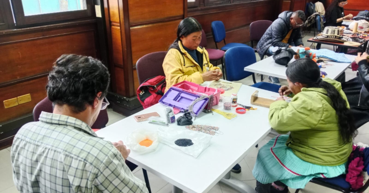 Imagen de varios artesanos trabajando sentados en una mesa