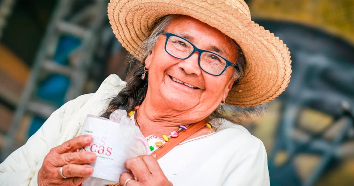 En la foto una mujer de la tercera edad feliz y tomando café