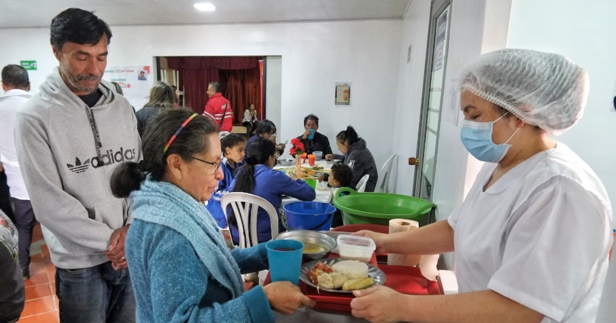 Imagen de una mujer recibiendo la bandeja del almuerzo