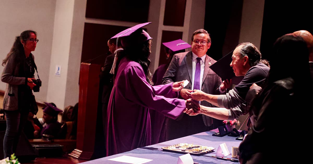 Foto de una de las graduandas recibiendo su diploma 
