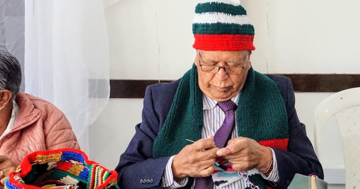 Imagen de una persona mayor tejiendo una bufanda navideña