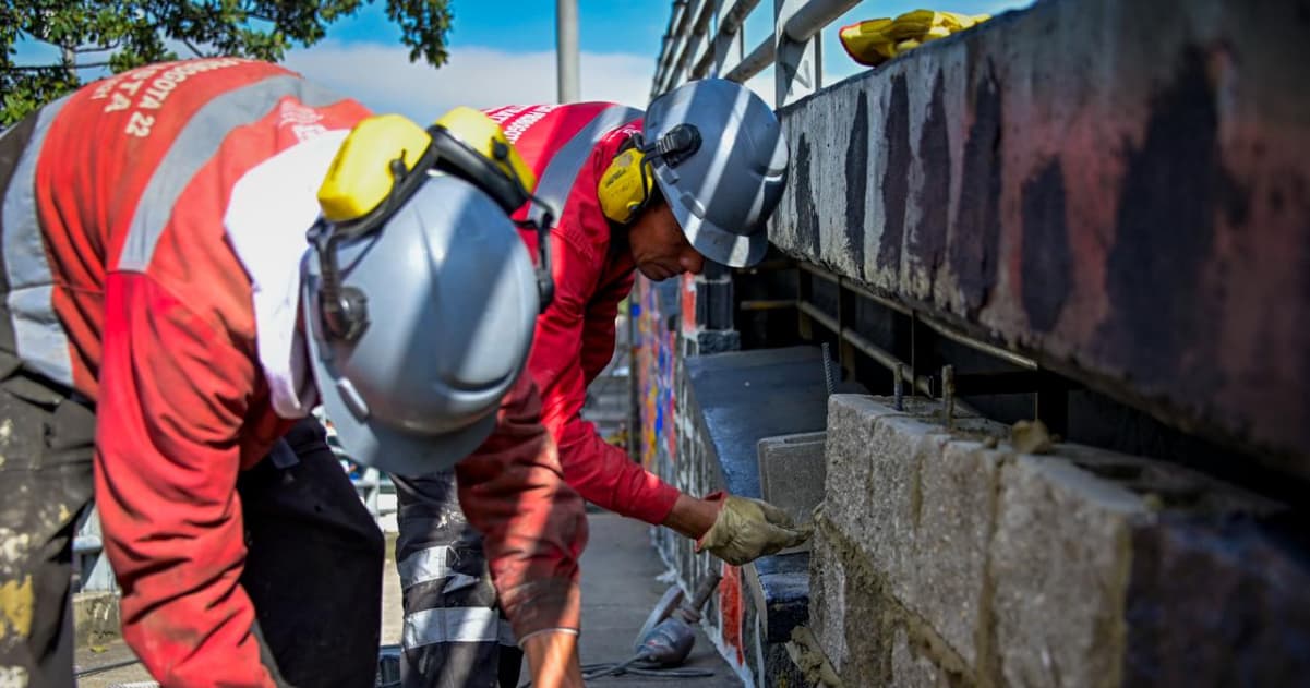 Trabajadores sellando huecos bajo el puente de la NQS con calle 19.