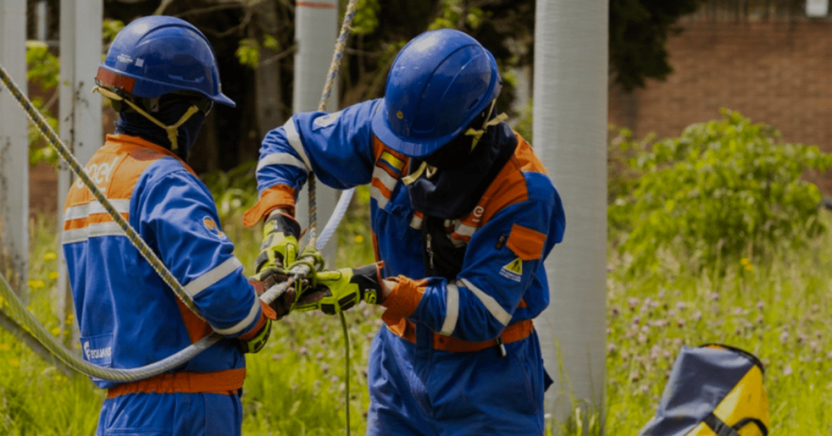 Imagen de varios técnicos de ENEL manipulando material en un poste en el que realizan su trabajo.
