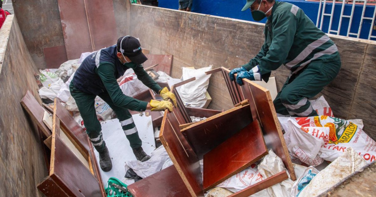 Foto que muestra dos personas recogiendo residuos 