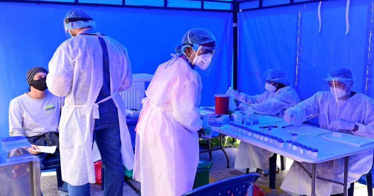 Foto que muestra un grupo de personas en una carpa con tapabocas