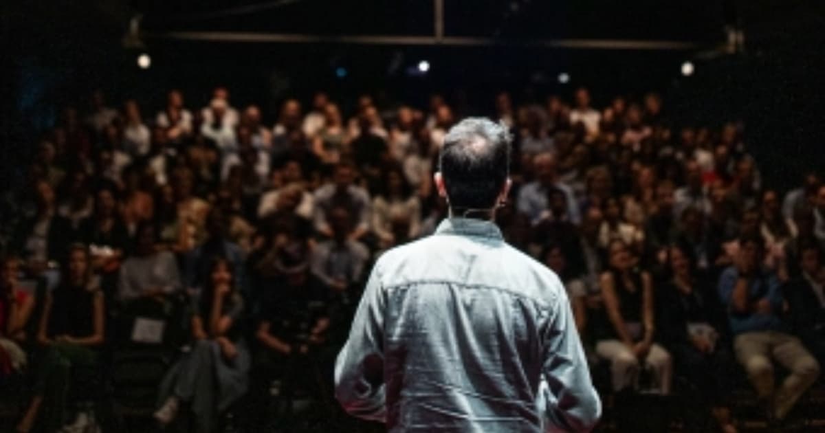 Foto de un hombre realizando una presentación ante un público en un audotorio.