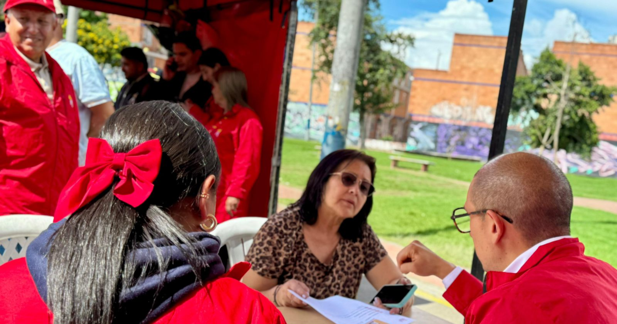 Imagen de funcionarios atendiendo a una señora en una mesa