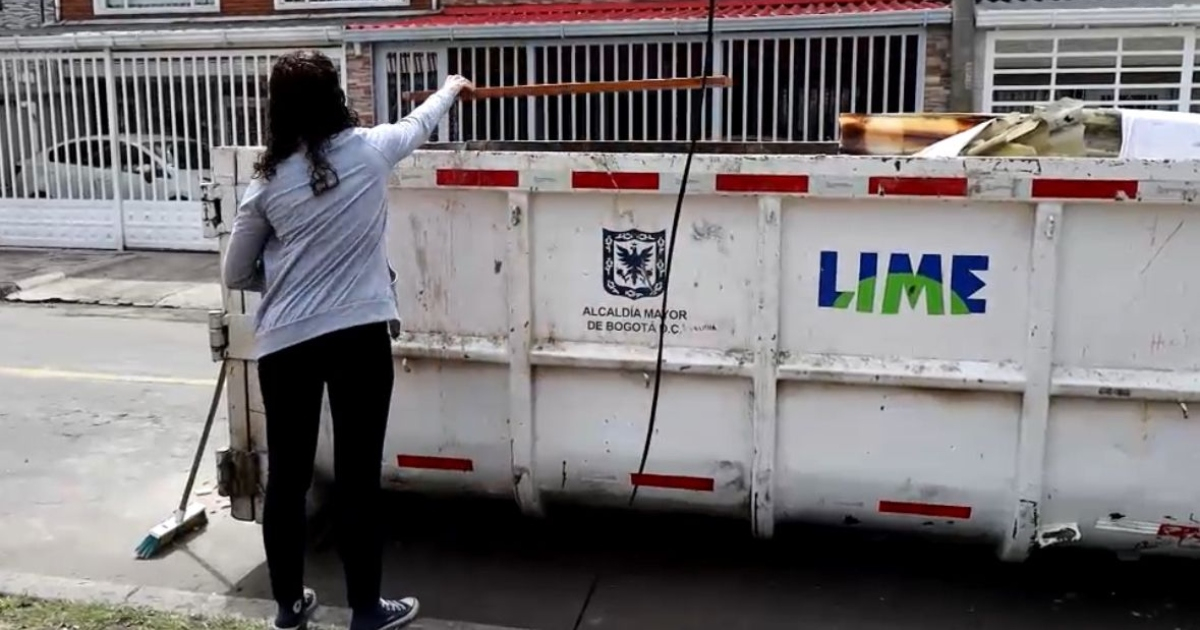 Foto que muestra un ecopunto y una ciudadana colocando residuos