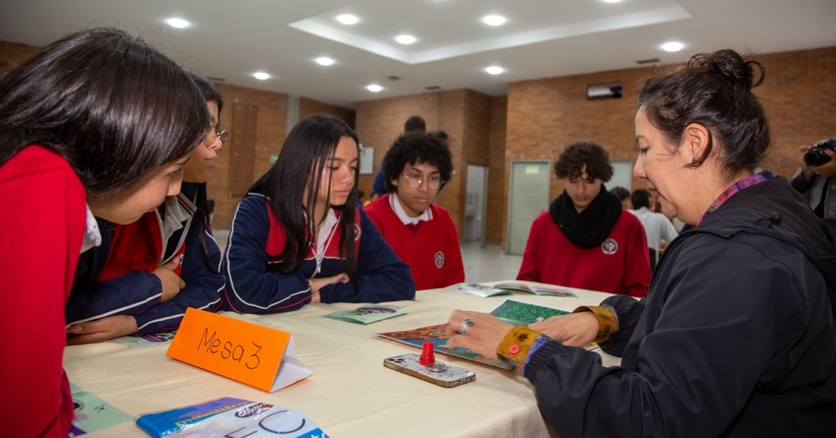 Foto que muestra estudiantes sentados en una mesa 