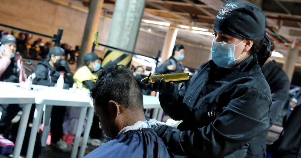 Imagen de una persona peluqueando a un habitante de calle