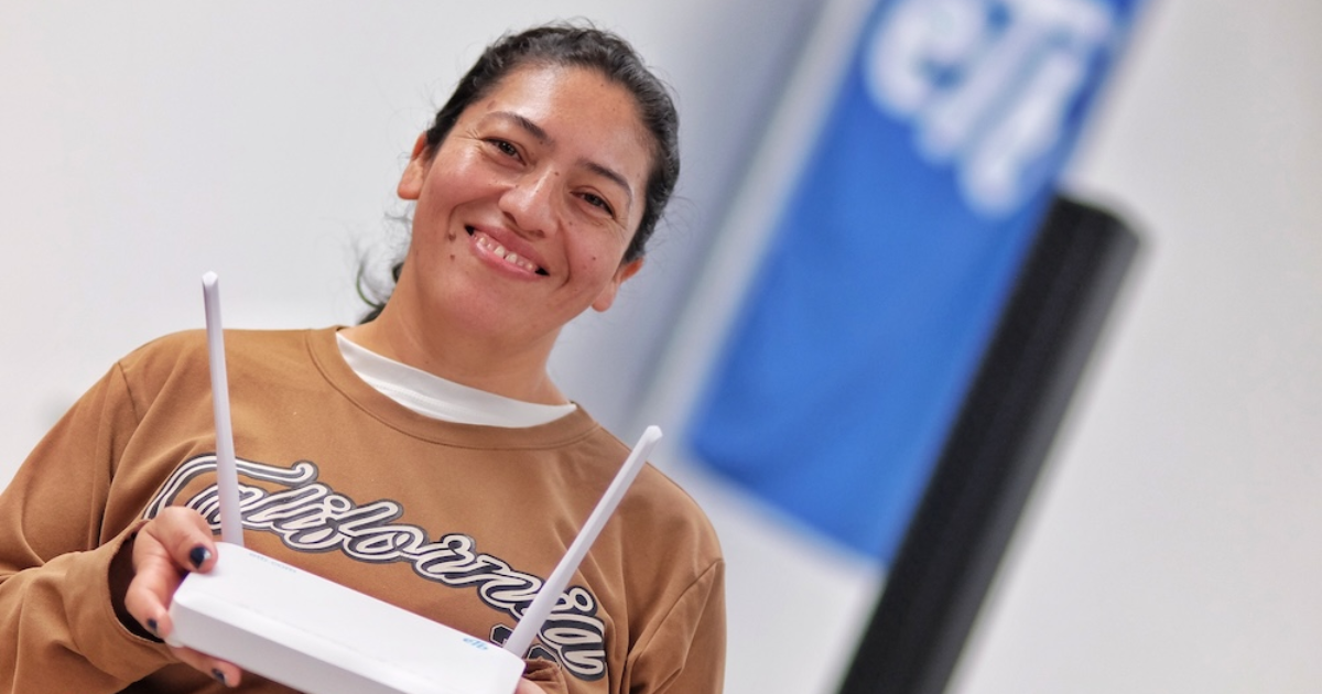 Imagen de una señora sonriendo y sosteniendo un rauter