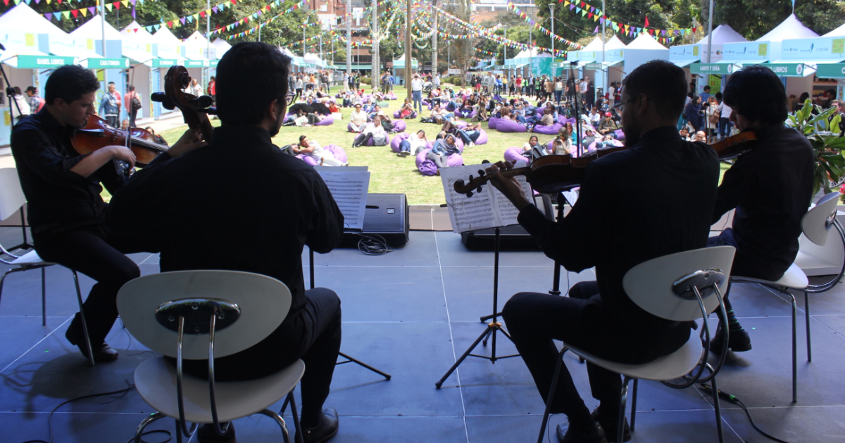 Imagen de un Grupo en tarima, de fondo se ve el público disfrutando de su presentación.