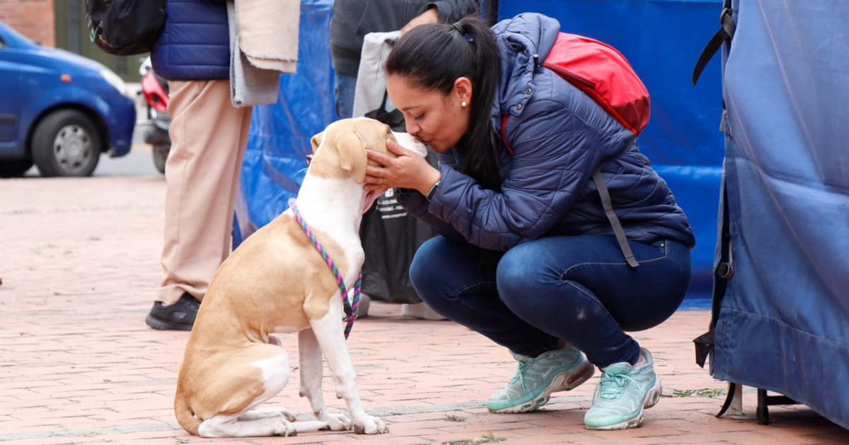 Una mujer dándole un beso a un perro