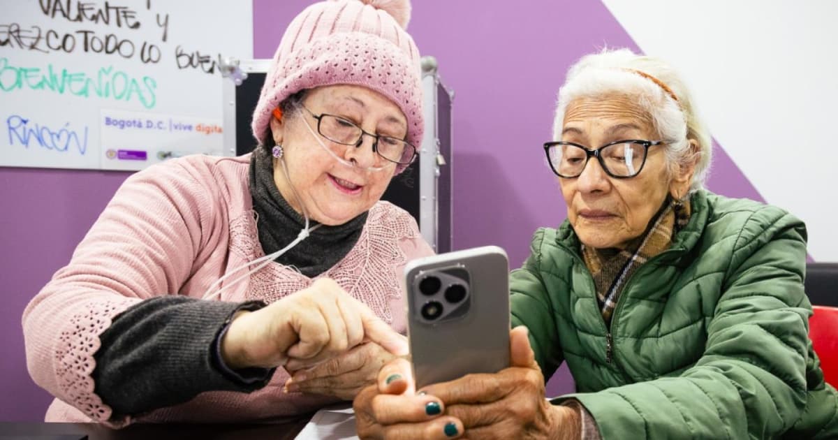 Dos mujeres mayores utilizando un celular en un proceso de capacitación en Bogotá.