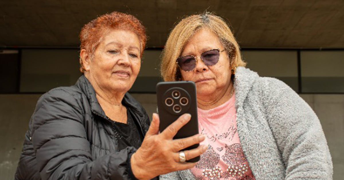 Imagen de dos mujeres adultas mayores viendo un celular