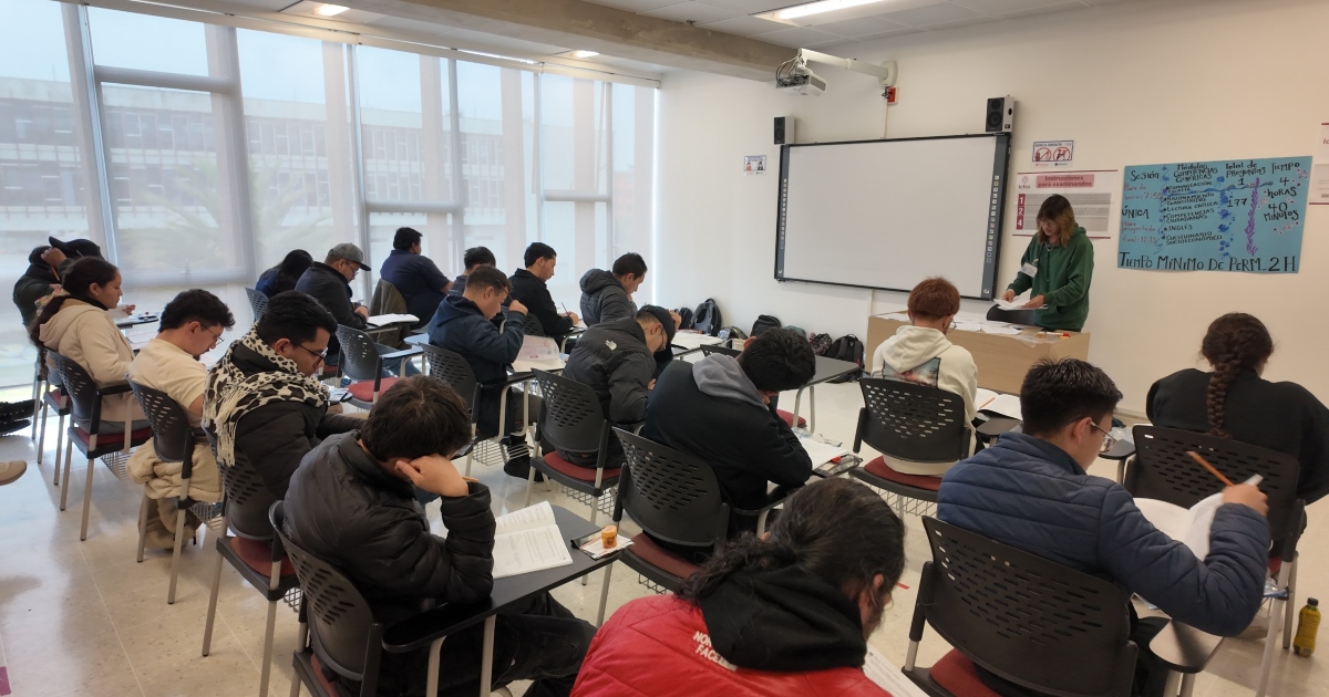 Foto que muestra estudiantes sentados en un salón 