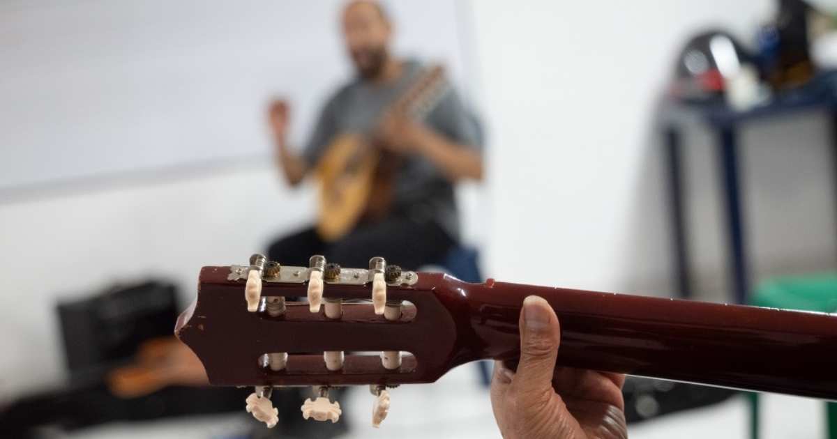 Foto que muestra una persona sosteniendo una guitarra