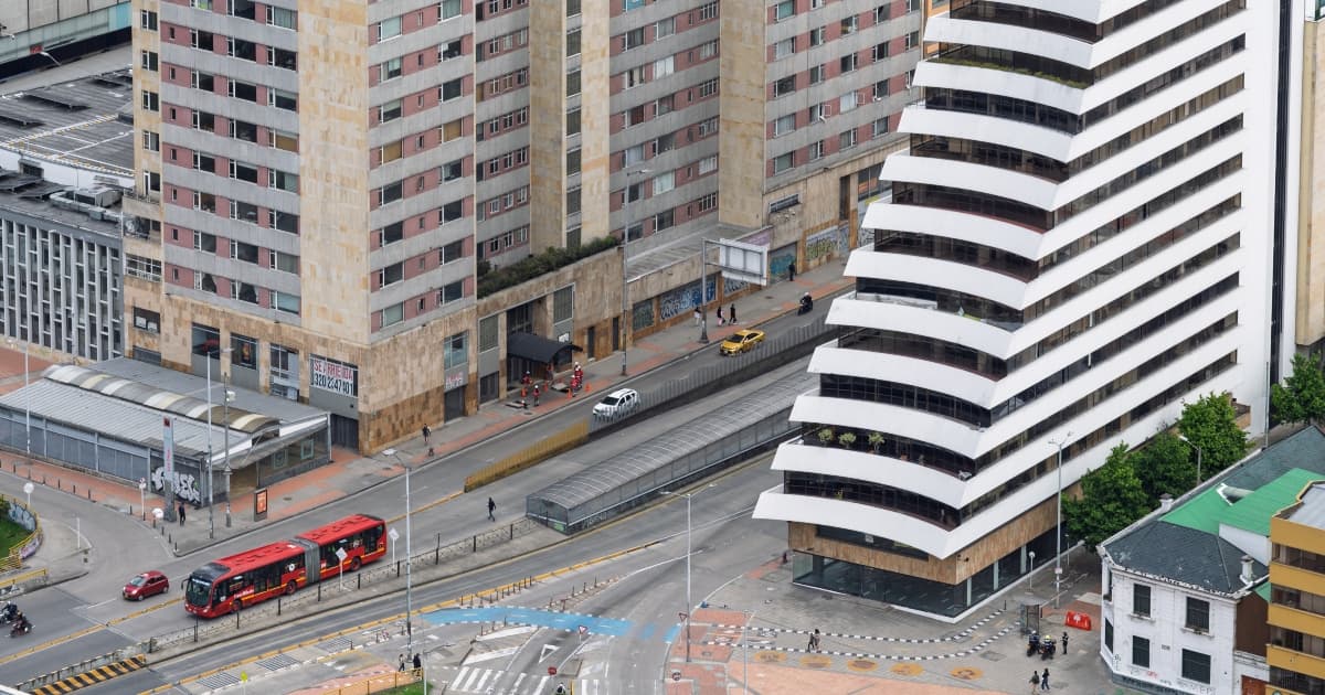 Avenida bogotana con buses TransMilenio, edificios altos y cruces peatonales desde arriba