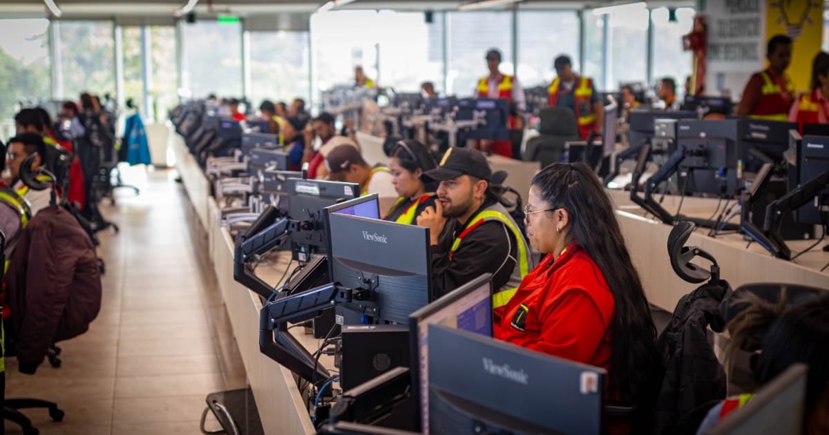 Funcionarios del Centro de Control de TransMilenio monitoreando desde computadores.
