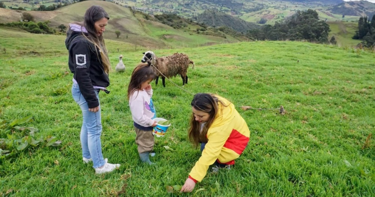 Imagen de una funcionaria junto con una señor y una niña en una área rural