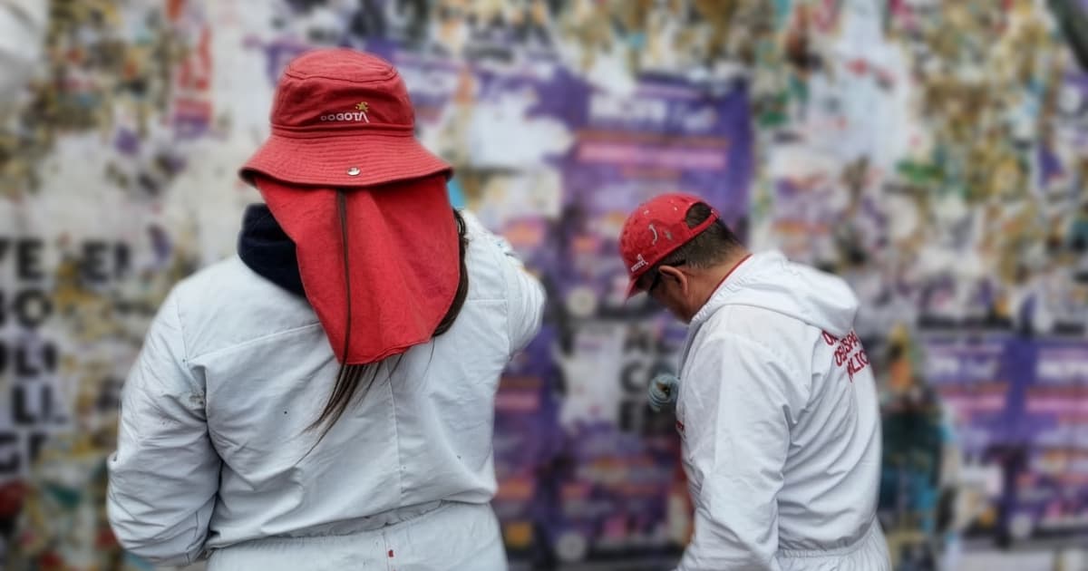 Dos defensores del espacio público retirando publicidad política ilegal del espacio público.