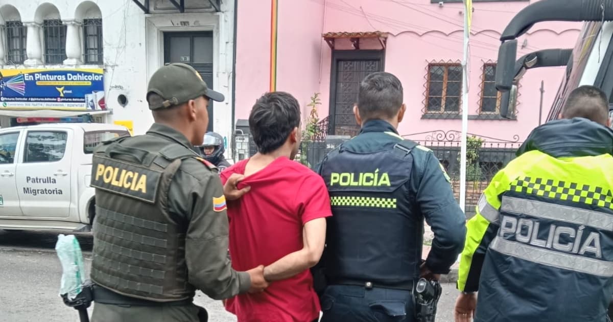 Hombre capturado durante el operativo, rodeado de tres policías.