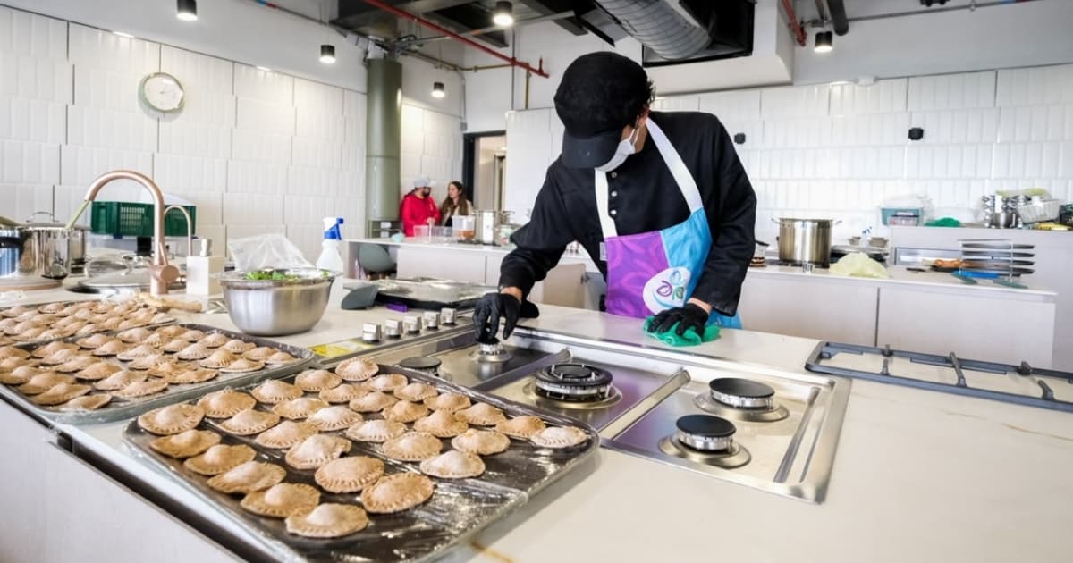 Persona prepara empanadas en aula culinaria del CEFE Cometas de Suba con estufas, bandejas y utensilios educativos